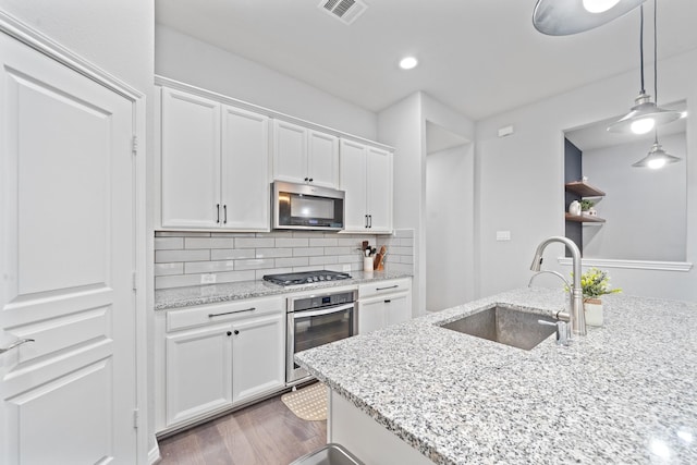 kitchen featuring visible vents, appliances with stainless steel finishes, tasteful backsplash, a sink, and white cabinets