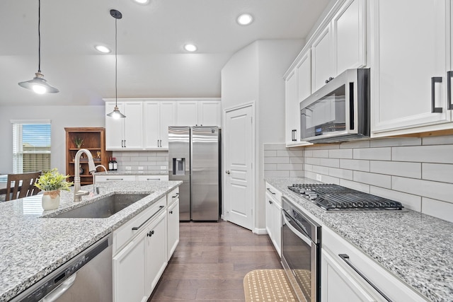 kitchen with dark wood-style flooring, white cabinets, a sink, appliances with stainless steel finishes, and hanging light fixtures