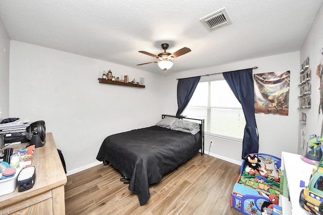 15519 Hensen Creek Dr, Houston, TX 77086 - bedroom featuring light wood-style flooring, baseboards, ceiling fan, and a textured ceiling