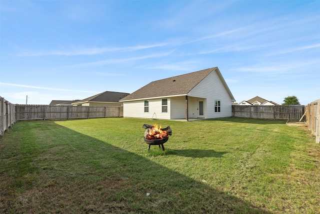 rear view of house featuring a lawn, a fenced backyard, and an outdoor fire pit