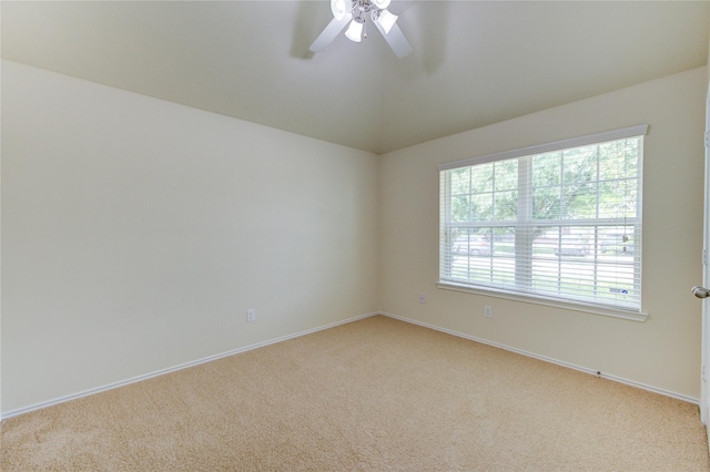 spare room with baseboards, a ceiling fan, vaulted ceiling, and light carpet