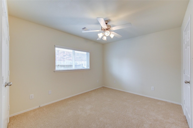 spare room featuring baseboards, ceiling fan, visible vents, and light colored carpet