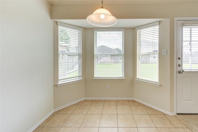 unfurnished dining area featuring baseboards, plenty of natural light, and light tile patterned floors