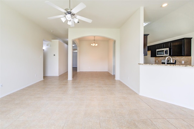 unfurnished living room featuring arched walkways, a ceiling fan, recessed lighting, and light tile patterned flooring