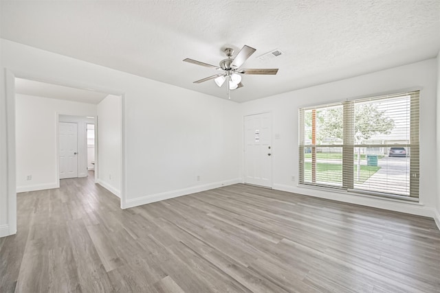 unfurnished room featuring visible vents, wood finished floors, baseboards, a textured ceiling, and a ceiling fan