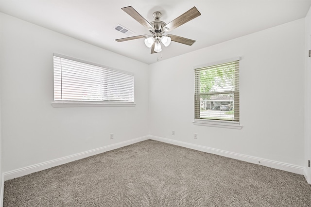 carpeted empty room featuring ceiling fan, visible vents, and baseboards