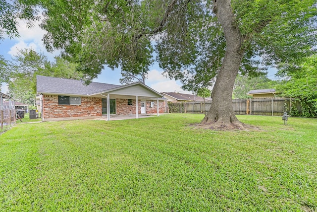 back of house featuring a patio, a fenced backyard, a yard, and brick siding