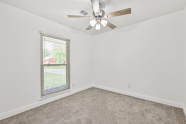 empty room with carpet floors, baseboards, a ceiling fan, and visible vents