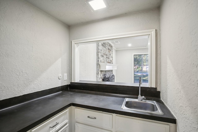 6531 Coral Ridge Rd, Houston, TX 77069 - kitchen with white cabinets, dark countertops, a textured wall, and a sink