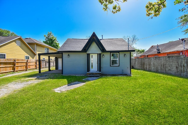 view of front facade featuring fence, dirt driveway, an attached carport, and a front lawn
