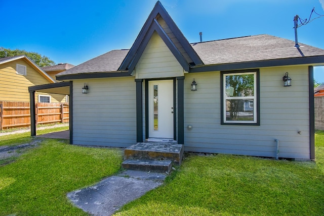 ranch-style home with fence, a shingled roof, and a front yard