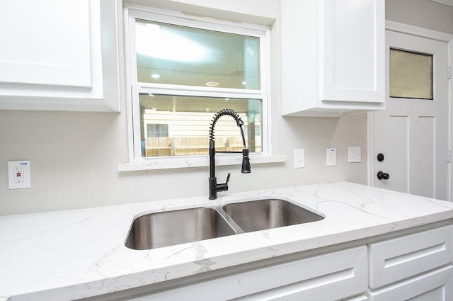 kitchen featuring a sink, white cabinetry, and light stone countertops