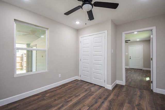 unfurnished bedroom with a closet, baseboards, and dark wood-style floors