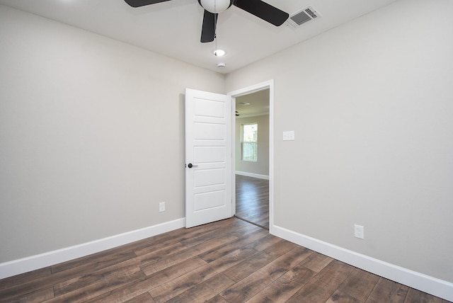 empty room with baseboards, ceiling fan, dark wood-style flooring, and visible vents