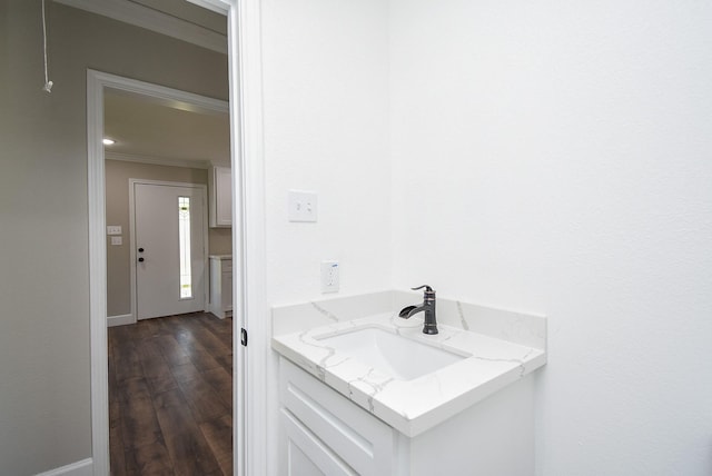 bathroom with ornamental molding, a sink, and wood finished floors