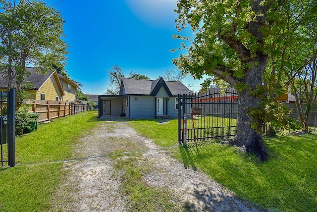 view of front of house featuring a gate, fence, driveway, and a front yard