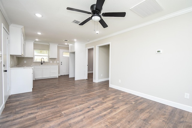 unfurnished living room featuring crown molding, visible vents, dark wood-style floors, and a sink