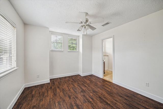 empty room featuring ceiling fan, a textured ceiling, baseboards, wood finished floors, and visible vents