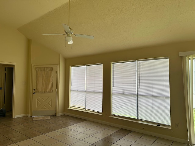 empty room featuring a ceiling fan, a textured ceiling, vaulted ceiling, light tile patterned floors, and baseboards