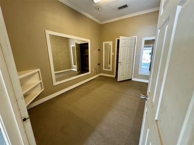 unfurnished room with baseboards, ornamental molding, dark carpet, and visible vents