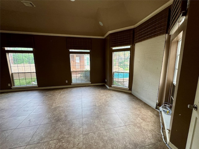 tiled empty room with visible vents, ornamental molding, baseboards, and lofted ceiling