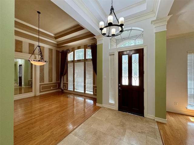 foyer entrance with an inviting chandelier, baseboards, crown molding, and a tray ceiling