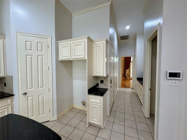 kitchen with white cabinetry, light tile patterned floors, tasteful backsplash, visible vents, and ornamental molding