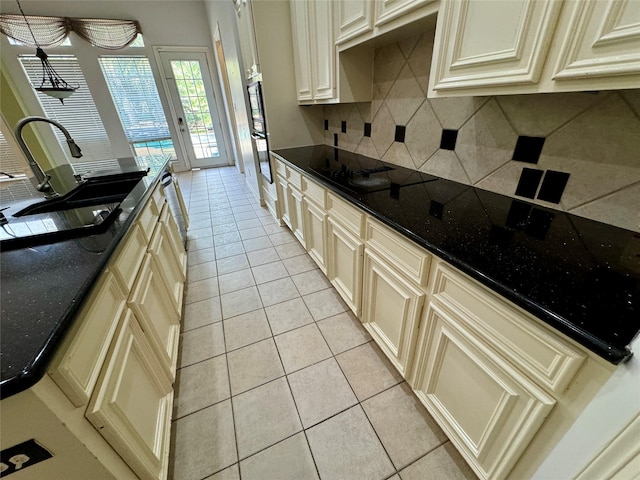 kitchen with cream cabinets, light tile patterned flooring, a sink, and tasteful backsplash