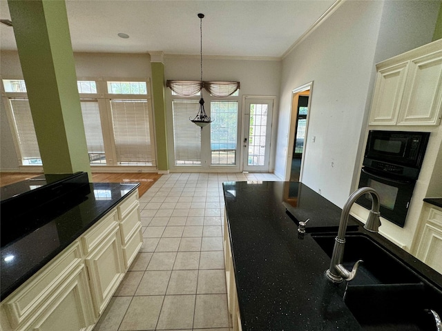 kitchen with a sink, dark stone countertops, light tile patterned floors, ornamental molding, and black appliances