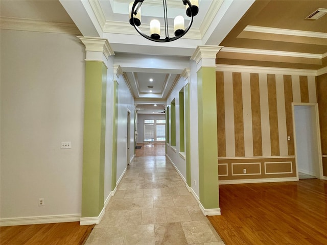 corridor with visible vents, ornamental molding, an inviting chandelier, ornate columns, and a raised ceiling