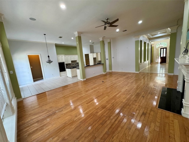 unfurnished living room featuring a ceiling fan, baseboards, light wood finished floors, ornamental molding, and recessed lighting