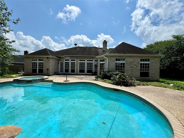 view of swimming pool featuring a pool with connected hot tub, fence, and a patio area