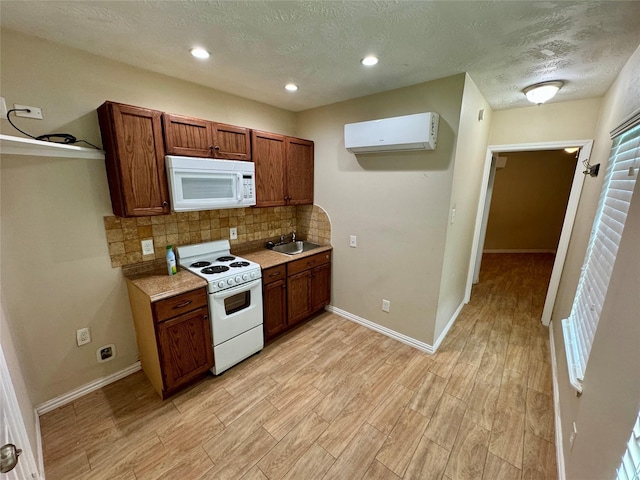 kitchen with a sink, light wood-style floors, white appliances, a wall mounted air conditioner, and decorative backsplash