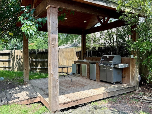 deck featuring area for grilling, an outdoor kitchen, a fenced backyard, and a sink