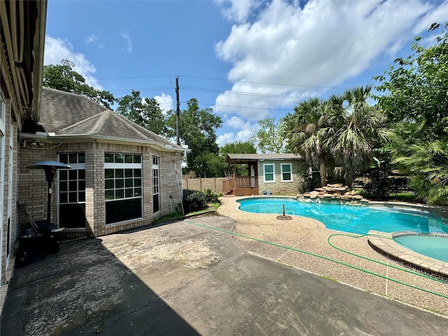 view of swimming pool with a patio, a pool with connected hot tub, and fence
