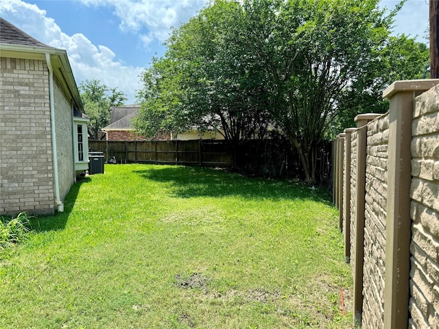 view of yard featuring a fenced backyard and central AC