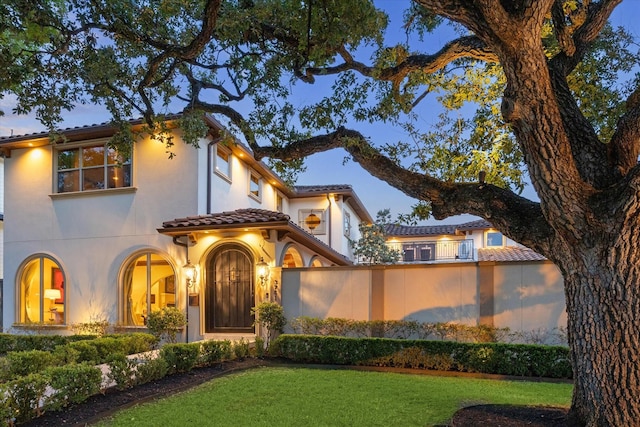 mediterranean / spanish home featuring stucco siding, a tile roof, and a front yard