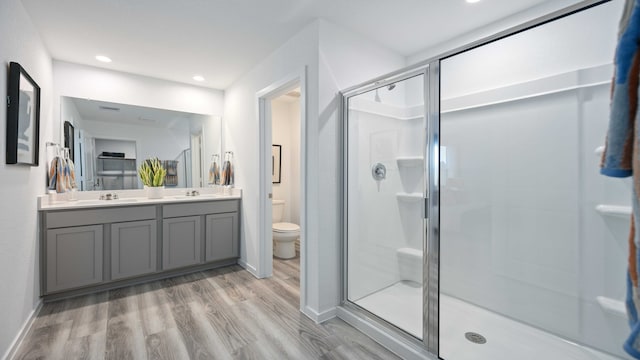 full bathroom with a sink, a stall shower, toilet, and wood finished floors