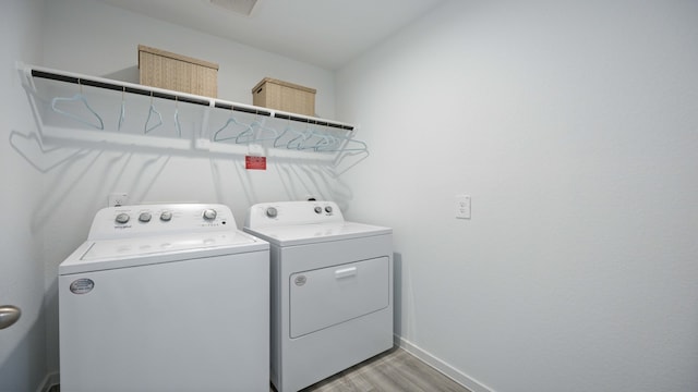 washroom featuring laundry area, light wood-type flooring, baseboards, and washing machine and clothes dryer