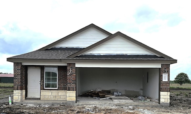 back of house with a shingled roof and brick siding
