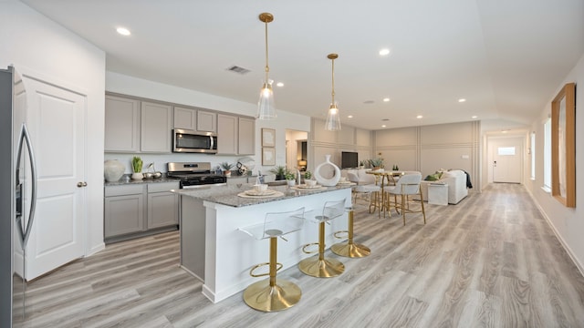 kitchen featuring stainless steel appliances, open floor plan, gray cabinetry, and light wood-style flooring