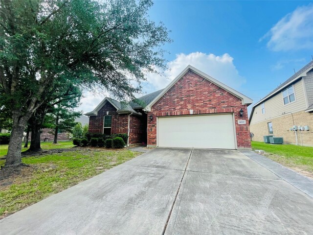 view of front of house with a front yard, central air condition unit, brick siding, concrete driveway, and an attached garage
