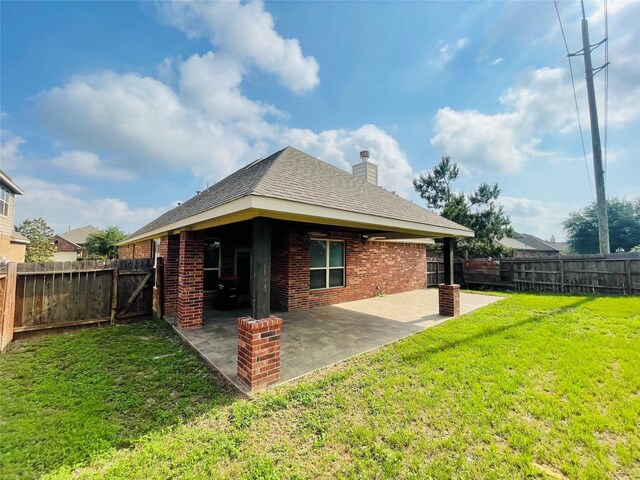 back of house featuring a fenced backyard, a chimney, a yard, and brick siding