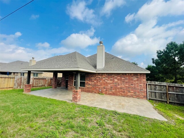 back of property featuring a patio, a fenced backyard, roof with shingles, brick siding, and a lawn