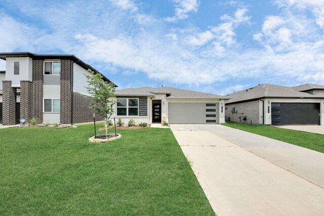 prairie-style house featuring a garage, concrete driveway, brick siding, and a front yard