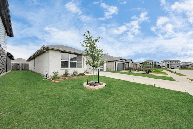 ranch-style house featuring fence, a front yard, brick siding, concrete driveway, and a residential view