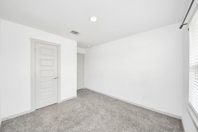 empty room with visible vents, carpet, and baseboards