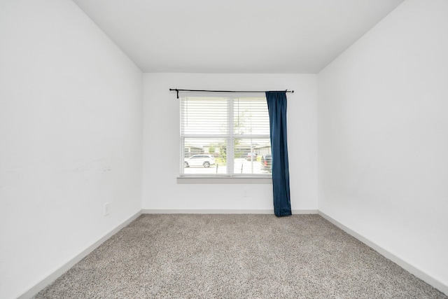 carpeted spare room featuring baseboards