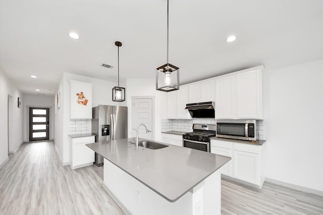 kitchen featuring backsplash, visible vents, appliances with stainless steel finishes, light wood-type flooring, and a sink