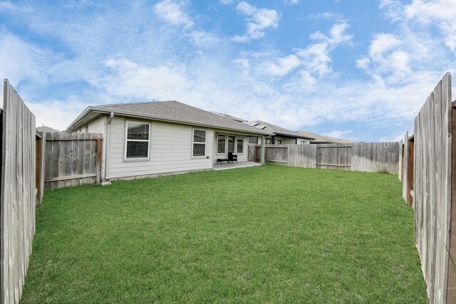 back of property with a fenced backyard, a patio, and a yard
